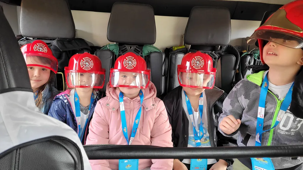 Children in red firefighter helmets.